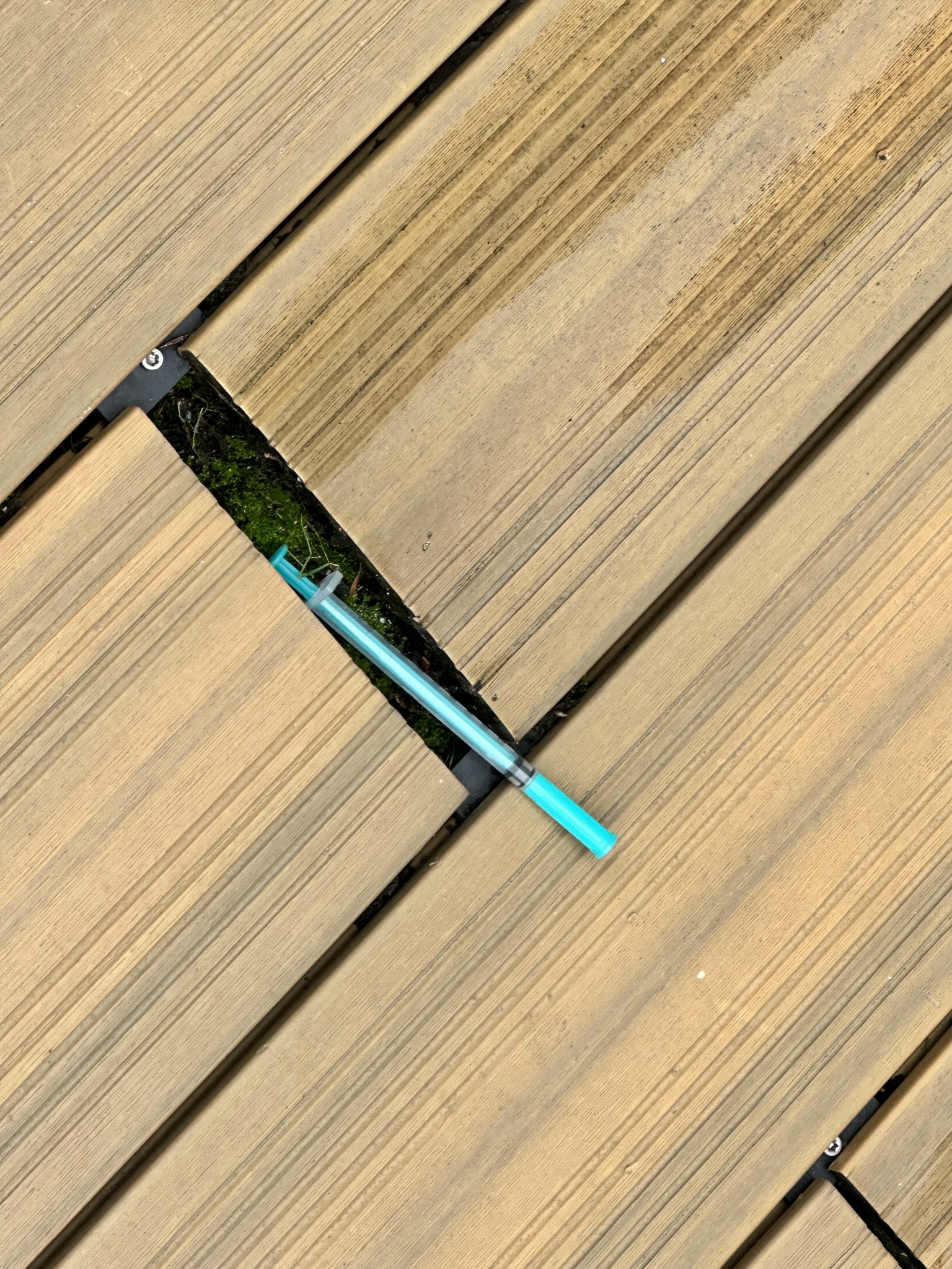 Discarded needle found between exterior decking boards during a commercial needle sweep in central Bristol